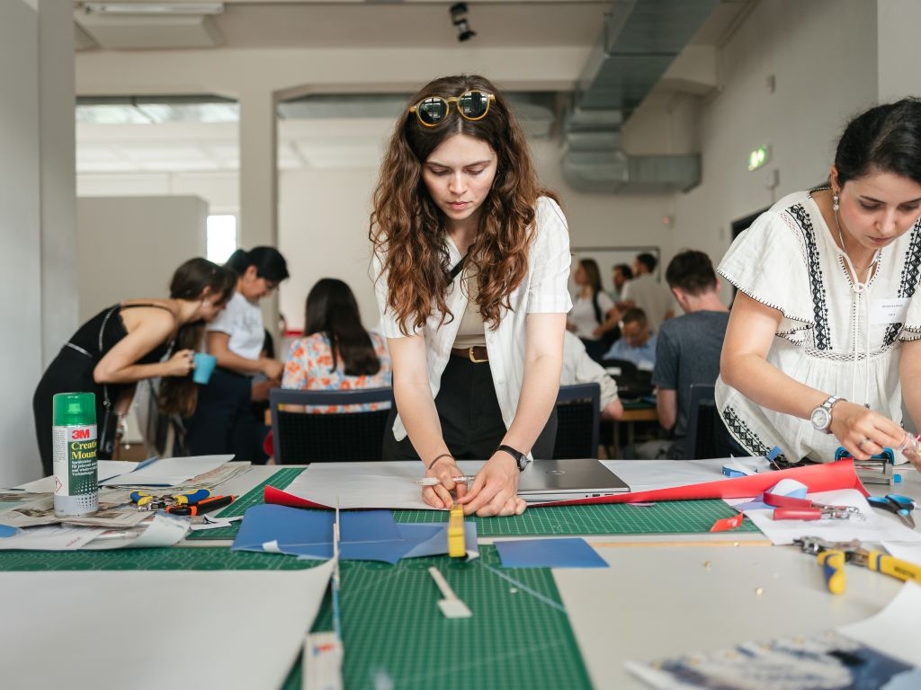 Kreativ Session beim GTO 2025: Eine Mitarbeiterin schneidet Stück aus einem alten Roll-Up 