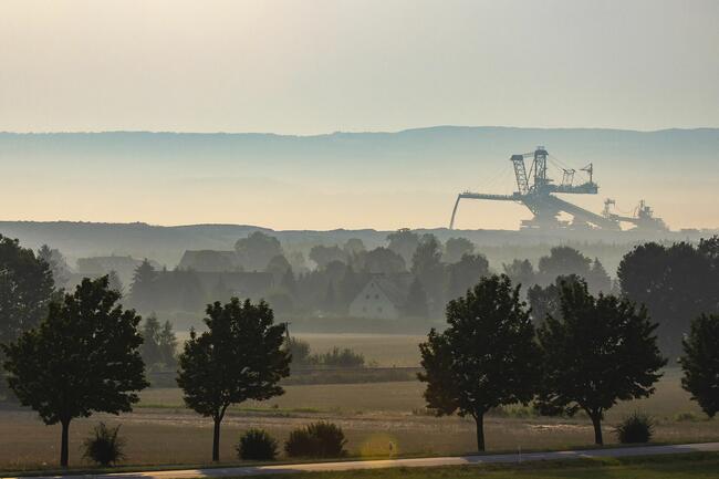 Blick übers Land. Im Hintergrund ist eine Förderbrücke eines Braunkohle Tagebauwerks zusehen