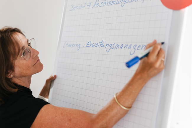 Eine Beraterin wie sie etwas auf eine Flipchart schreibt 