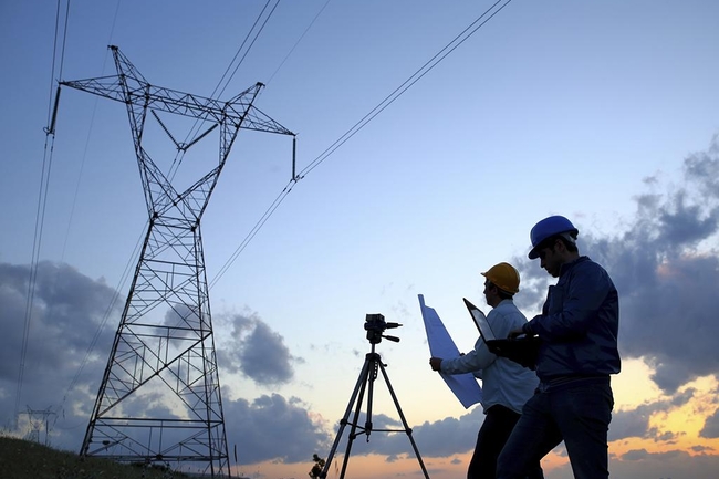 zwei Ingenieure arbeiten bei Sonnenuntergang vor einem Elektrizitätswerk