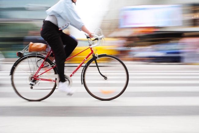 Eine Frau fährt auf einem Rennrad auf einer Straße, der Hintergrund ist verschwommen.