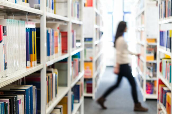 JUnge Frau läuft durch eine Bibliothek