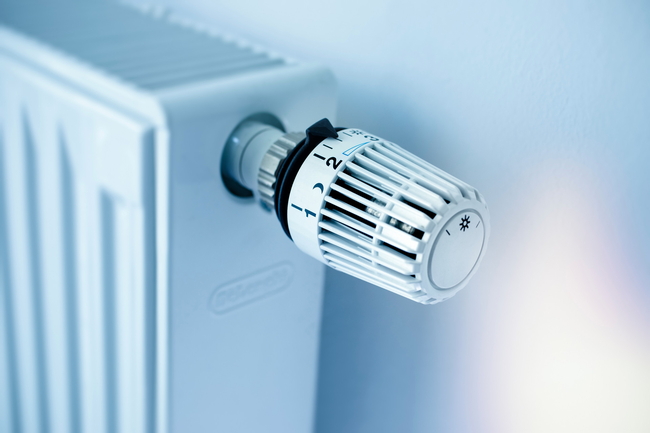 Weißer Flachheizkörper mit Thermostat an der Wand in einer Wohnung.