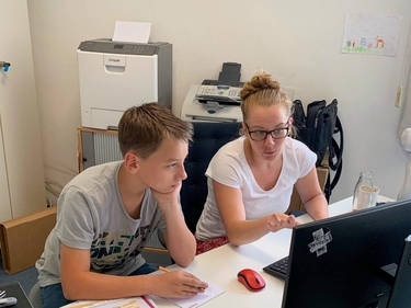 Prognos Mitarbeiterin erklärt dem Schüler etwas am Computer