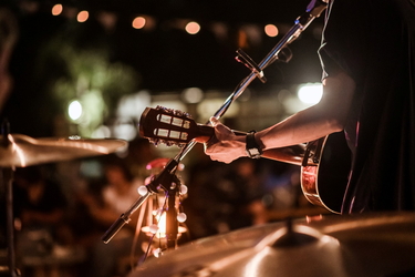Ein Musiker spielt auf einer Open-Air-Bühne Gitarre. 